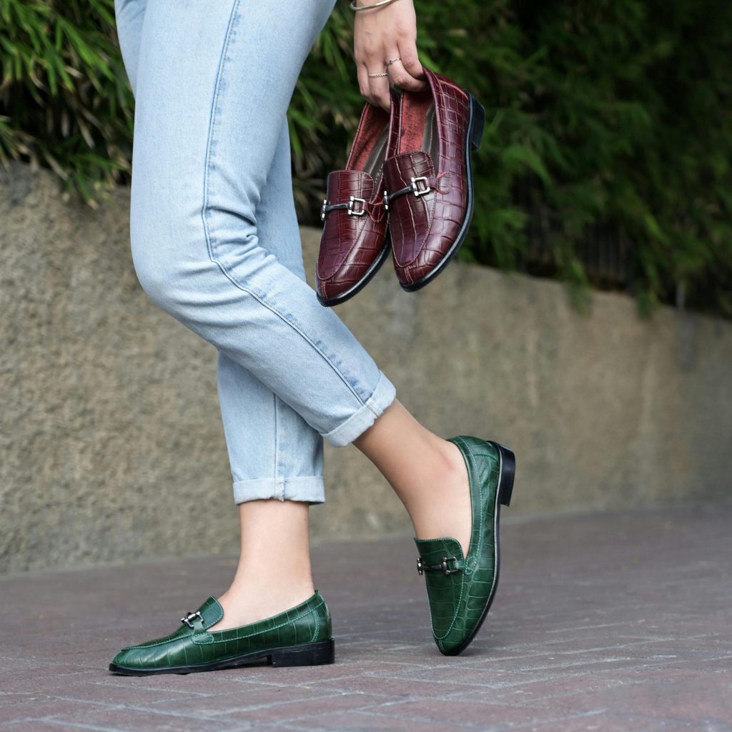 comfortable and trendy outfits for older women lady carrying red shoes loafers, and wearing green flat shoes