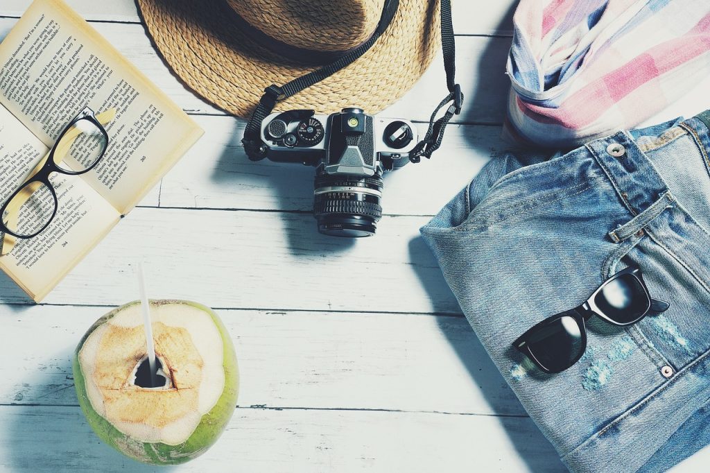 stylish travel looks layering essentials Travel outfits for women, camera, cococut, book and glasses, hat